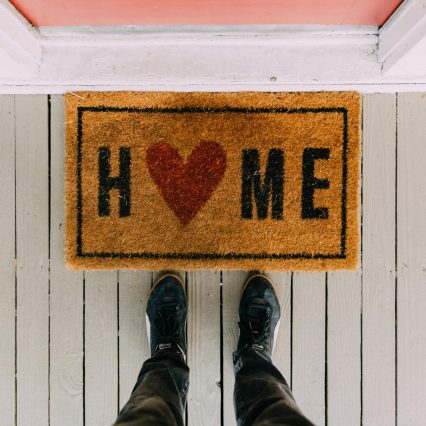 A creative doormat with heart motif symbolizing home at a front porch entrance.